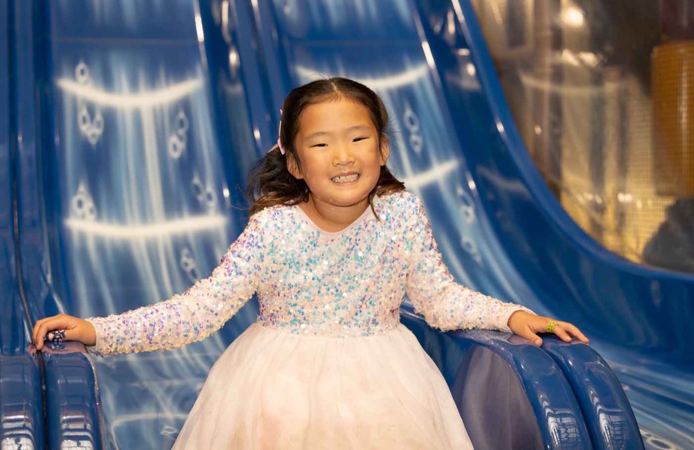 A smiling kid on the blue slide at Safari Run San Mateo